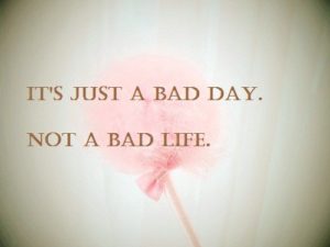 A sign with a flower in the background that says "It's just a bad day, not  bad life"